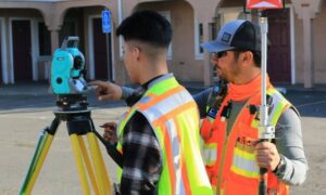 Land surveyors measuring a property with equipment before redevelopment work begins