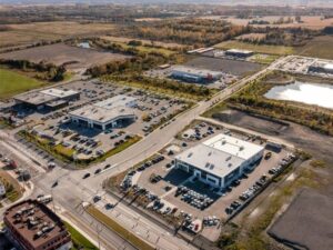 Aerial view of a commercial property with parking lots, access roads, and surrounding development areas