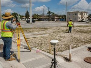 Survey crew collecting elevations, utility locations, and drainage data during a topographic survey in Hialeah, Florida.