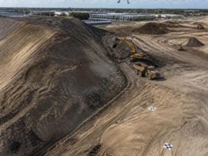 Survey drone mapping an active earthwork site with stockpiles and ground control points in Hialeah, Florida.