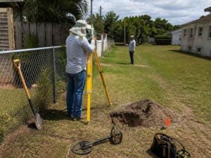 Land surveyors using a total station and metal detector to locate a missing property monument in Hialeah, Florida.
